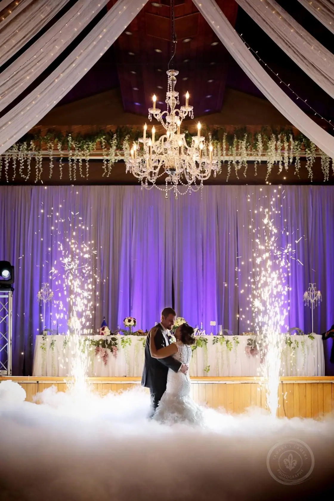 First dance in a fog cloud with sparkler fountains and purple uplighting behind the head table