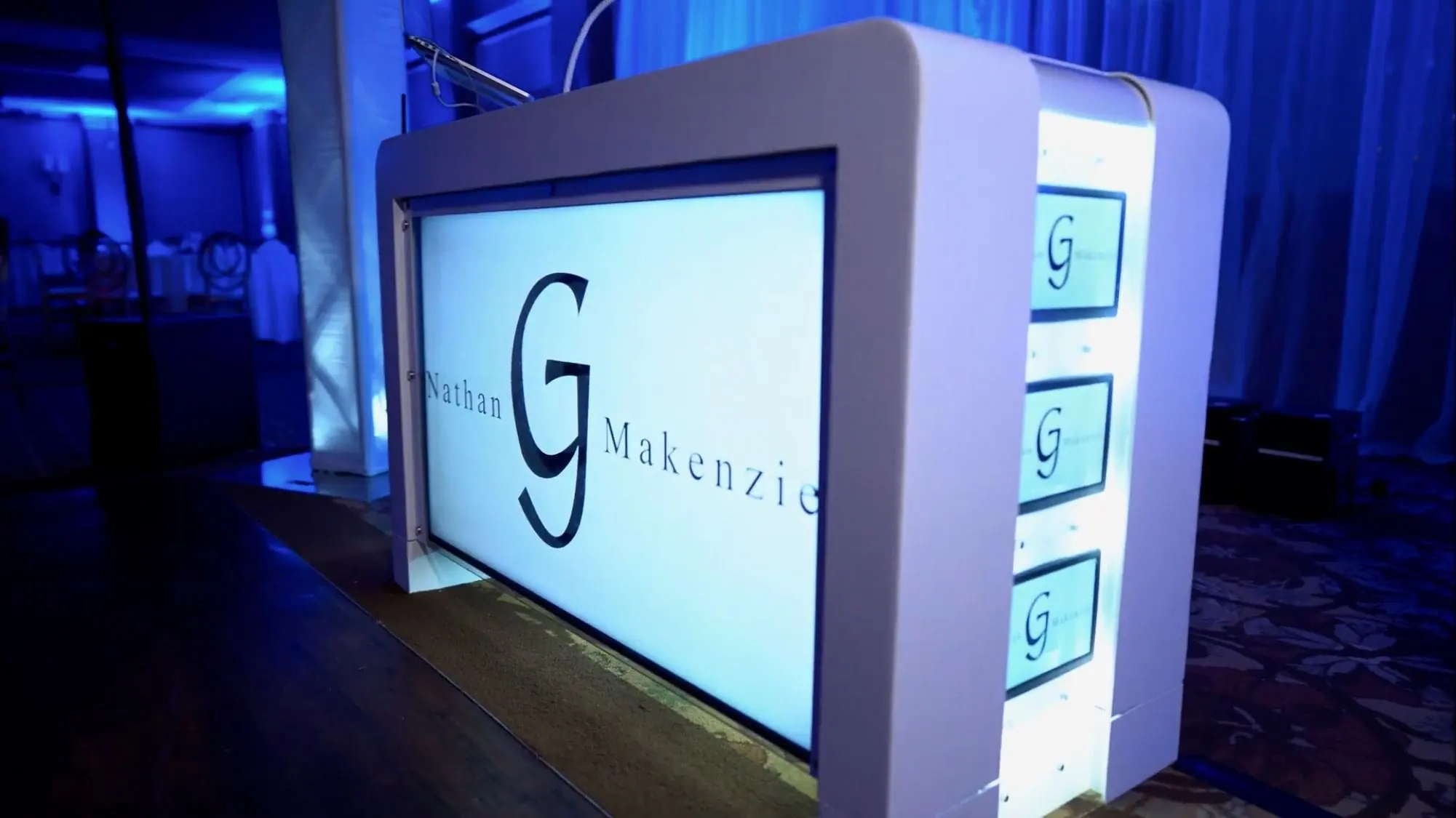 Video DJ booth with a large front screen and side screens under blue uplighting